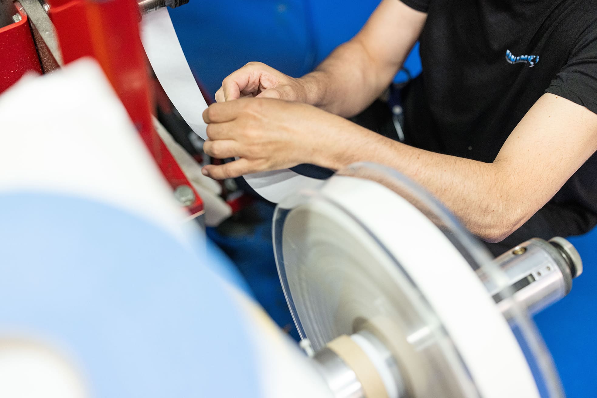 Técnico de Equymelt manipulando una bobina de cinta adhesiva en el proceso de rebobinado industrial.